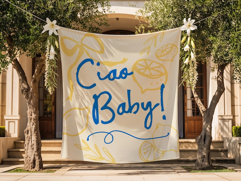 Puede incluir: Una pancarta color crema con las palabras "Ciao Baby!" en escritura azul, acentuada con ilustraciones de limones y lazos amarillos. La pancarta est&aacute; suspendida entre dos &aacute;rboles, decorada con flores blancas y vegetaci&oacute;n, frente a un edificio.