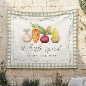 May include: A green and white checkered banner with a white background featuring a cartoon onion, carrot, beet, and corn with smiling faces. The text reads "a little sprout -is on the way-"