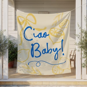 Puede incluir: Una pancarta color crema con las palabras "Ciao Baby!" en escritura azul. Ilustraciones de limones amarillos y un dise&ntilde;o de lazo rodean el texto. La pancarta est&aacute; colgada afuera, con olivos en macetas a ambos lados.