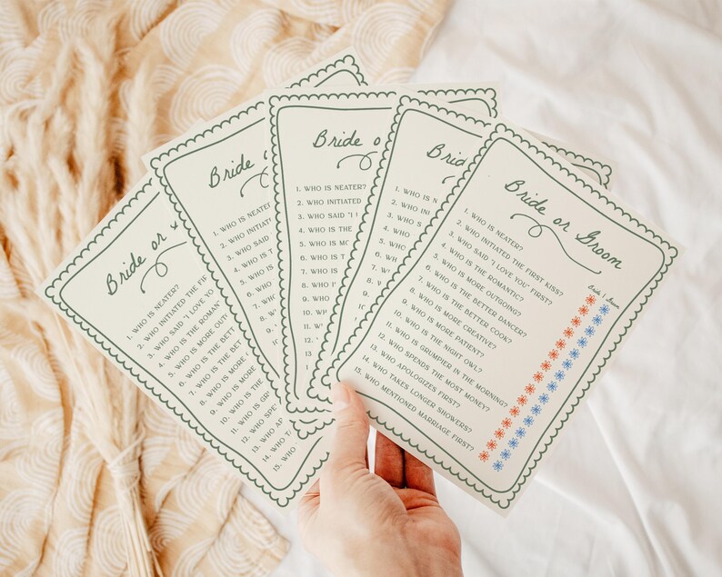 May include: A set of off-white paper game cards titled Bride or Groom with a scalloped border. Each card features a list of fifteen questions and two columns of small red and blue star icons for marking answers to the wedding-themed trivia game.
