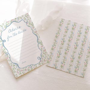 Może przedstawiać: Dwie karty z kwiatowym wzorem. Jedna karta zawiera tekst "Advice for the Bride" w niebieskiej ramce, z liniami do pisania. Druga karta ma pionowy wz&oacute;r w paski z małymi kwiatami. Karty są białe z r&oacute;żowymi, niebieskimi i zielonymi akcentami kwiatowymi.