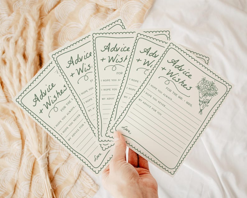 May include: A collection of cream-colored advice and wishes cards with green text and a scalloped border. The cards feature the text "Advice + Wishes" and prompts for the recipient to fill out. A bouquet illustration is on one card. The cards are held in a hand.