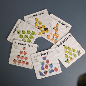 May include: Five square cards featuring cartoon fruit characters arranged in pyramids. Text includes: You're the APPLE of my pie, Simply the Zest!, It Takes 2 to Mango, A-peach-iate You, Be your Berry Best!, and the PEAR SHAPED. Each card has labels for counts.