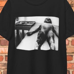 Area 51 alien shirt featuring a UFO autopsy design inspired by Roswell and sci-fi themes. Perfect for paranormal and X-Files fans, this graphic tee is a great gift for alien lovers and conspiracy enthusiasts.
