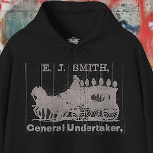 May include: Black hooded sweatshirt with a vintage-style graphic print of a horse-drawn hearse and the text "E. J. SMITH, General Undertaker."