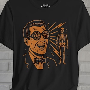 Könnte beinhalten: Schwarzes T-Shirt mit einer orangefarbenen Illustration eines Mannes mit Röntgenbrille, der lächelt, mit einem Skelett im Hintergrund. Der Text "X-RAY SPECS" steht auf der Brille. Der Mann trägt eine Fliege.