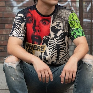 May include: A short-sleeve crew neck t-shirt featuring a graphic collage print. The design includes a red face with wide eyes, a black and white skeleton, and green textured accents. The text "WHERE IS" and "YOU" is visible on the front.