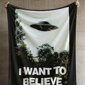 May include: Black fleece blanket with a white UFO and the text "I WANT TO BELIEVE" printed on it.