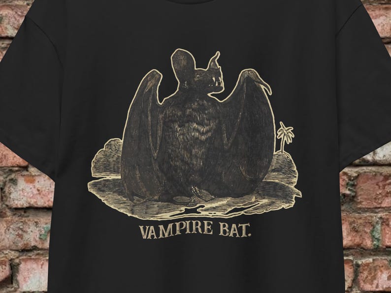 May include: A black t-shirt with a vintage illustration of a vampire bat in a gold color. The text "Vampire Bat." is printed below the image.