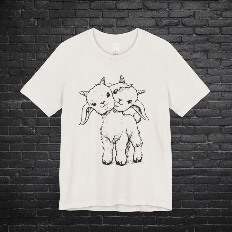 Two-headed goat graphic t-shirt featuring a vintage-inspired design. Perfect for fans of animals, punk fashion, and weird or unusual oddities. Comfy, short-sleeved unisex tee for men and women.