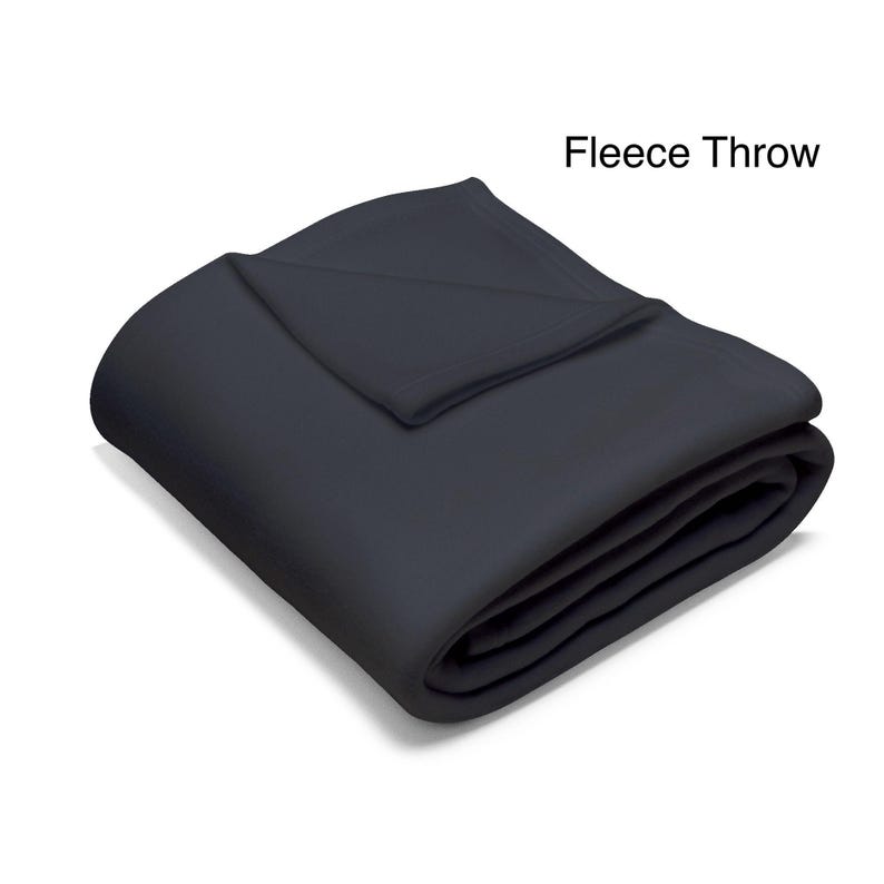 May include: A folded, dark gray fleece throw blanket. The blanket is neatly folded, with the top layer showing a folded-over edge. The words "Fleece Throw" are in the upper right corner.