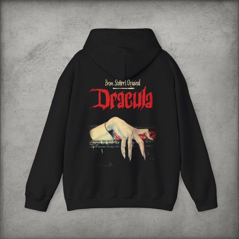 May include: A black hooded sweatshirt featuring a graphic print on the back. The text reads Bram Stoker's Original Dracula in red and white lettering. Below the text is an illustration of a pale hand with long fingernails resting on a dark edge.