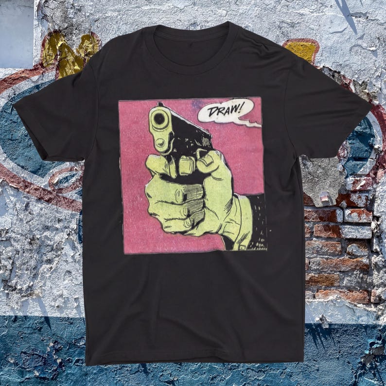 a black t-shirt with a graphic design depicting a hand holding a gun and the word "DRAW!" written above it.