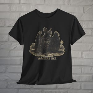 May include: Black t-shirt with a gold graphic of a vampire bat with outstretched wings. The text "Vampire Bat" is printed below the bat.
