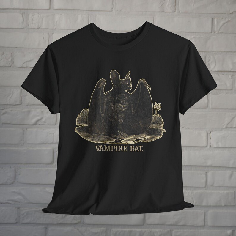 May include: Black t-shirt with a gold graphic of a vampire bat with outstretched wings. The text "Vampire Bat" is printed below the bat.
