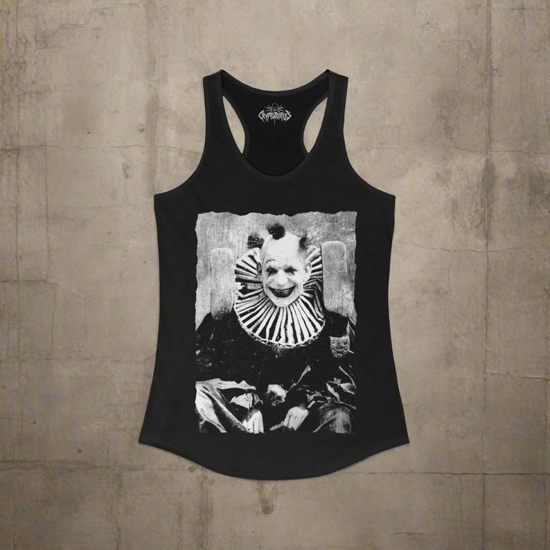 May include: A black racerback tank top featuring a high-contrast, black and white graphic print of a clown wearing a ruffled collar. The clown has a wide, toothy grin and dark eye makeup. The text Cryptidous is printed inside the neckline.