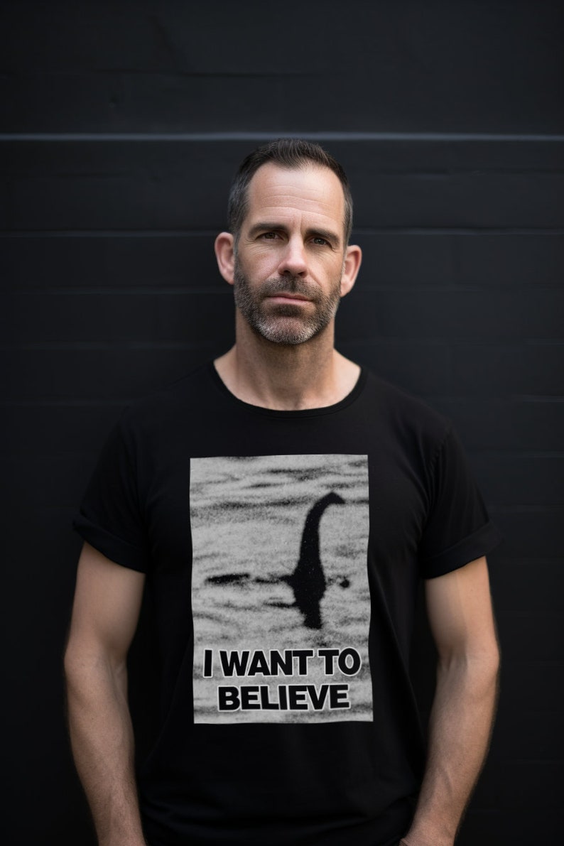 Model showcases a cryptozoology-inspired Loch Ness shirt, with a vivid depiction of Nessie and the phrase "I Want to Believe", blending intrigue and style for lake monster fans and mystery lovers.
