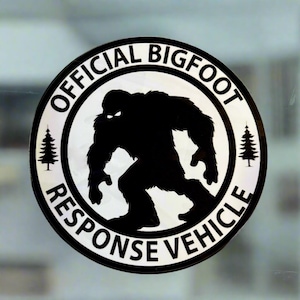 May include: A black and white sticker with the text "Official Bigfoot Response Vehicle" in a circle. A silhouette of Bigfoot is in the center of the circle, walking to the right. There are two small pine trees on either side of the Bigfoot.