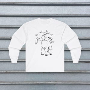 Alternative punk shirt with a creepy two-headed goat design. Distressed vintage horror-inspired graphic tee for goths, metal fans, and occult enthusiasts. Unisex weird fashion gift for oddity lovers.