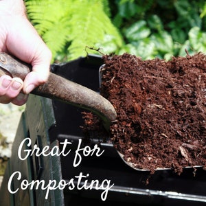May include: A person using a shovel to scoop dark brown compost from a black compost bin. The text "Great for Composting" is visible in the image.