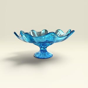 May include: A vibrant blue glass pedestal bowl featuring a wide, shallow basin with a distinctively ruffled, scalloped edge. The bowl is supported by a short, sturdy, fluted stem that connects to a circular base, all crafted from translucent glass.