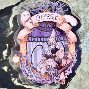 Può includere: Un ciondolo in acrilico illustrato con un personaggio con un cappello da mago, che scrive in un libro. Il ciondolo ha uno striscione con la scritta "Qifrey". Il design include un gufo, pergamene e una lanterna, con una combinazione di colori viola e arancione.