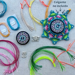 Puede incluir: Un mandala de macramé colorido con un diseño de vitral en el centro. El kit incluye varios colores de hilo de bordar, cuentas plateadas y una pieza redonda de vitral. El texto "Colgante no incluido" está escrito en español en la imagen.