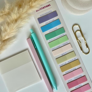 Peut inclure: Un ensemble de papeterie avec un stylo bleu clair, un stylo rose et un ensemble de notes autocollantes colorées. Les notes autocollantes sont étiquetées avec des termes français tels que "Important" et "Citations". Un trombone doré et un bloc-notes vierge sont également présents.