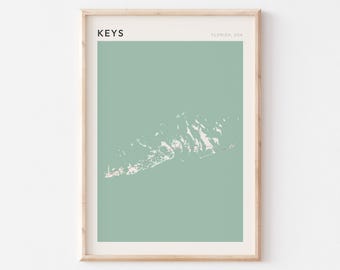 Könnte beinhalten: Ein gerahmter Kunstdruck mit einer minimalistischen Karte der Florida Keys. Die Karte ist weiß und rosa auf einem gedämpften grünen Hintergrund. Das Wort "KEYS" steht oben links, mit "FLORIDA, USA" oben rechts.