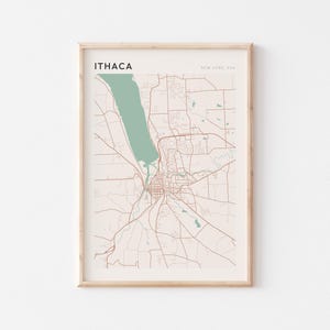 May include: Framed map print of Ithaca, New York, USA. The map features a detailed layout of the city with roads and waterways in shades of brown and green. The word "ITHACA" is printed at the top.