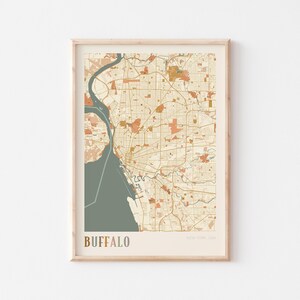 Peut inclure: Une impression encadrée d'une carte de Buffalo, New York, dans une palette de couleurs neutres. La carte présente une représentation détaillée de la disposition de la ville, avec les routes, les cours d'eau et les points de repère. Le mot "BUFFALO" est imprimé en bas.