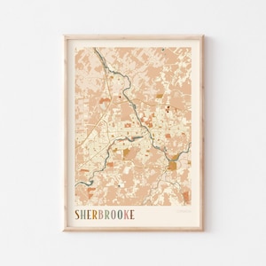 May include: A framed map print of Sherbrooke, Canada, in a muted color palette of peach, beige, and brown. The map details the city's layout, with roads and buildings. The word "SHERBROOKE" is printed at the bottom in a multi-colored font.