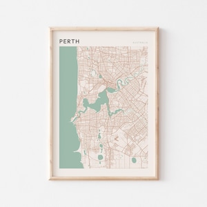 Puede incluir: Impresión enmarcada de un mapa de Perth, Australia. El mapa presenta un diseño detallado de las calles en tonos marrones y beige, con una sección turquesa que representa la costa y una masa de agua. La palabra "PERTH" está impresa en la parte superior.