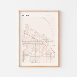 May include: A framed map print of Indio, California, USA. The map features a detailed street layout in shades of brown and beige, with the city name in a bold, black font. The print is encased in a light-colored wooden frame.