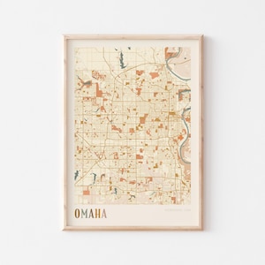 Puede incluir: Impresión enmarcada del mapa de Omaha, Nebraska, en una paleta de colores neutros. El mapa presenta diseños detallados de calles, parques y el río Missouri. La palabra "OMAHA" está impresa en la parte inferior.