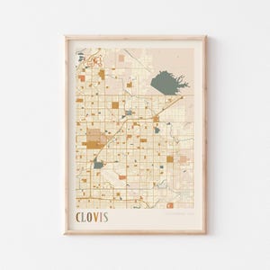 Puede incluir: Impresión enmarcada de un mapa de Clovis, California, EE. UU. El mapa presenta un patrón de cuadrícula con carreteras y edificios en tonos beige, marrón y azul. La palabra "CLOVIS" está impresa en la parte inferior.
