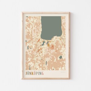 Può includere: Stampa incorniciata della mappa di Jönköping, Svezia, in una palette di colori neutri. La mappa presenta un grande lago e i dettagli della città circostante in tonalità beige, pesca e verde oliva. La parola "JÖNKÖPING" è stampata in basso con lettere colorate.