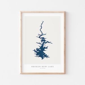 May include: A framed print featuring a navy blue illustration of Broken Bow Lake in Oklahoma. The lake's outline is depicted against a cream-colored background. The text "BROKEN BOW LAKE OKLAHOMA" is printed at the bottom.