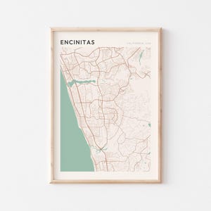 May include: A framed map print of Encinitas, California, USA. The map shows a detailed road network in brown against a cream background, with a green coastal area on the left. The word "ENCINITAS" is printed at the top.