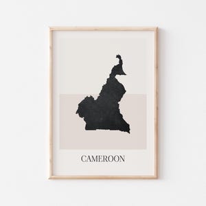 May include: Framed art print featuring a black silhouette of Cameroon on a neutral background. The country's name is printed in a simple font at the bottom. The artwork is encased in a light wood frame.