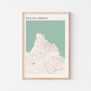 May include: A framed map print of Pacific Grove, California, USA. The map features a detailed street layout in brown against a light beige background, with a green section representing the ocean. The text "PACIFIC GROVE" is at the top.