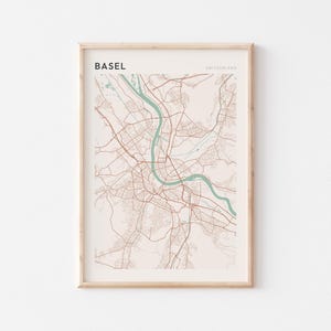 Peut inclure: Une impression encadrée de la carte de Bâle, Suisse. La carte présente un réseau de rues et de routes marron, avec une rivière turquoise qui la traverse. Le mot "BASEL" est imprimé en noir en haut à gauche, et "SUISSE" en gris en haut à droite.