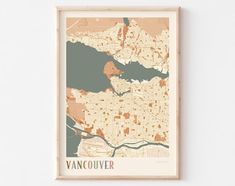 May include: A framed map print of Vancouver, Canada, featuring a color palette of muted peach, cream, and dark sage green. The city layout is depicted with grid lines and water bodies, with the text VANCOUVER printed in bold letters.