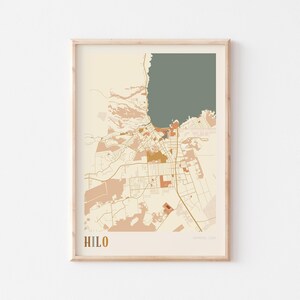 Può includere: Una stampa incorniciata della mappa di Hilo, Hawaii, USA, in stile minimalista. La mappa presenta uno sfondo beige con accenti marroni, arancioni e verdi. La parola "HILO" è stampata in oro in basso a sinistra.