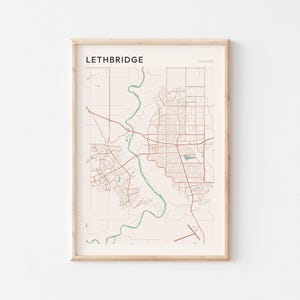 Puede incluir: Impresión enmarcada del mapa de Lethbridge, Canadá, en un estilo minimalista. El mapa presenta carreteras y contornos de la ciudad en marrón sobre un fondo beige, con un río turquesa. La palabra "LETHBRIDGE" está impresa en la parte superior, con "CANADA" a la derecha.