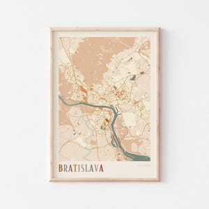 May include: A framed map print of Bratislava, Slovakia, in a neutral color palette. The map features a detailed depiction of the city's layout, including roads, rivers, and buildings. The word "BRATISLAVA" is printed in a brown font at the bottom.