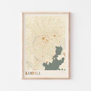 Könnte beinhalten: Ein gerahmter Kartendruck von Kampala, Uganda, in neutralen Tönen. Die Karte zeigt detaillierte Straßennetze und geografische Merkmale, mit einem Wasserabschnitt in gedämpftem Grün. Das Wort "KAMPALA" ist gedruckt.