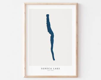 May include: A framed print featuring a minimalist blue illustration of Seneca Lake, New York, against a cream background. The lake's shape is depicted with a single, continuous line. The text "SENECA LAKE NEW YORK" is printed at the bottom.