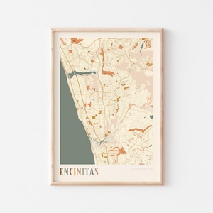 May include: A framed map print of Encinitas, California, in a minimalist style. The map features a muted colour palette of beige, orange, and green, with the city name at the bottom. The print is in a wooden frame.