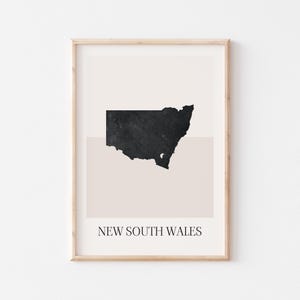 May include: Framed art print featuring a black and textured outline of New South Wales, Australia, set against a beige and white background. The words "NEW SOUTH WALES" are printed in a minimalist font at the bottom.